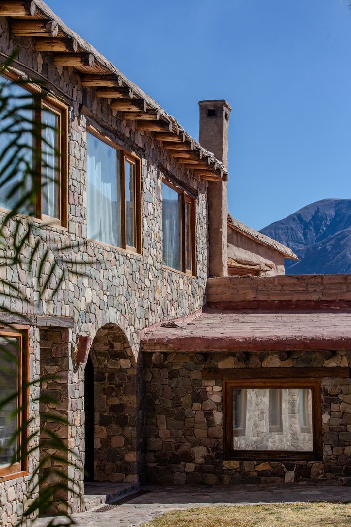 Fachada en piedra y madera con la Quebrada de fondo